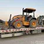 Side view of John Deere 310L backhoe loader on a trailer — shipment to Durban