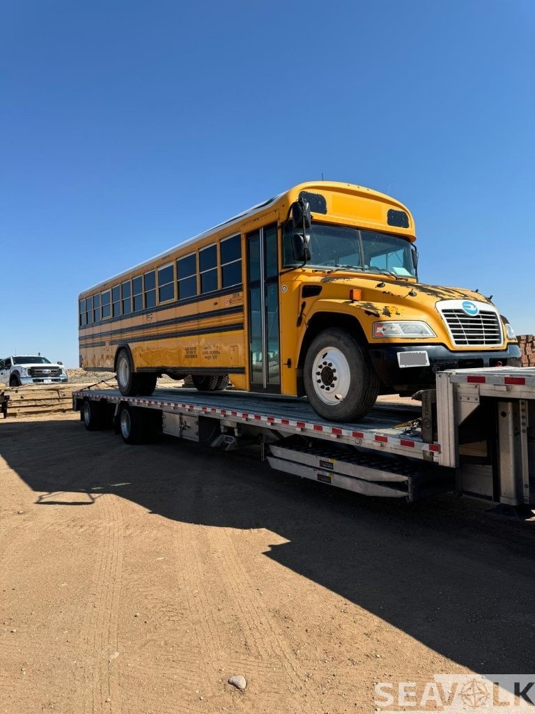 Used school bus on a step-deck trailer, front view — Oklahoma to Nicaragua shipment