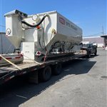 Towable Stoltz Site Spreader — A white Stoltz Site Spreader with its own axle group and towing frame is shown from two angles. View 1.