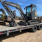 Volvo Compact Excavator — A compact Volvo excavator is photographed with its boom folded, blade lowered and bucket supported on the trailer.