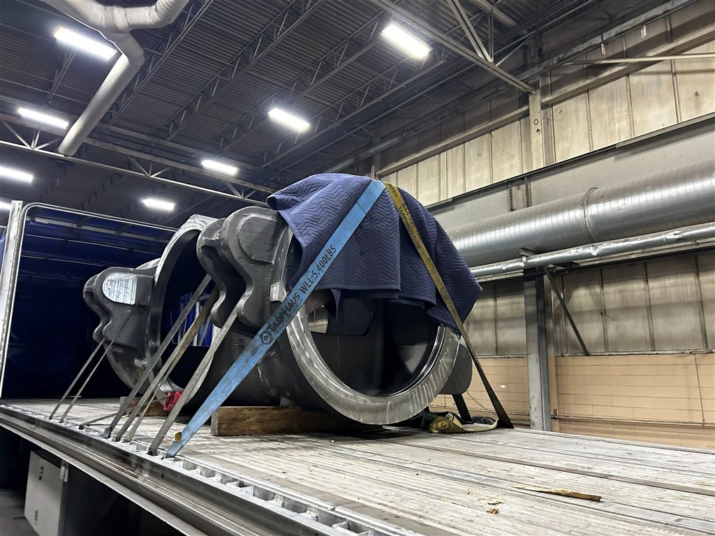 Heavy Engine Component: A large cast-metal engine component photographed during loading preparation (view 1)