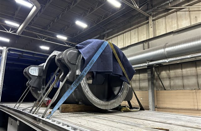 Heavy Engine Component: A large cast-metal engine component photographed during loading preparation (view 1)